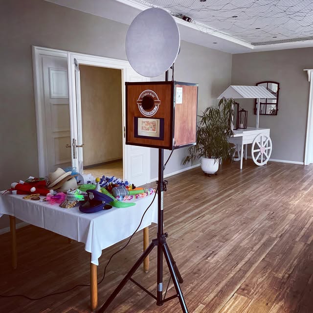 Originalaufnahme unserer Holzfotobox auf schwarzem Stativ mit rundem weißem Lichtschirm und Requisitentisch